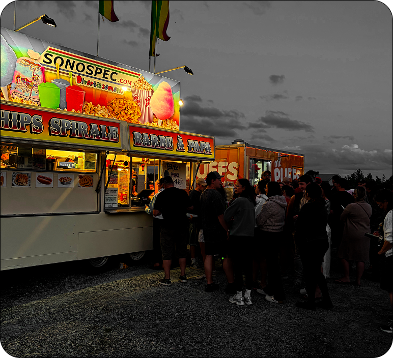 Queue in front of brightly lit food trucks at night